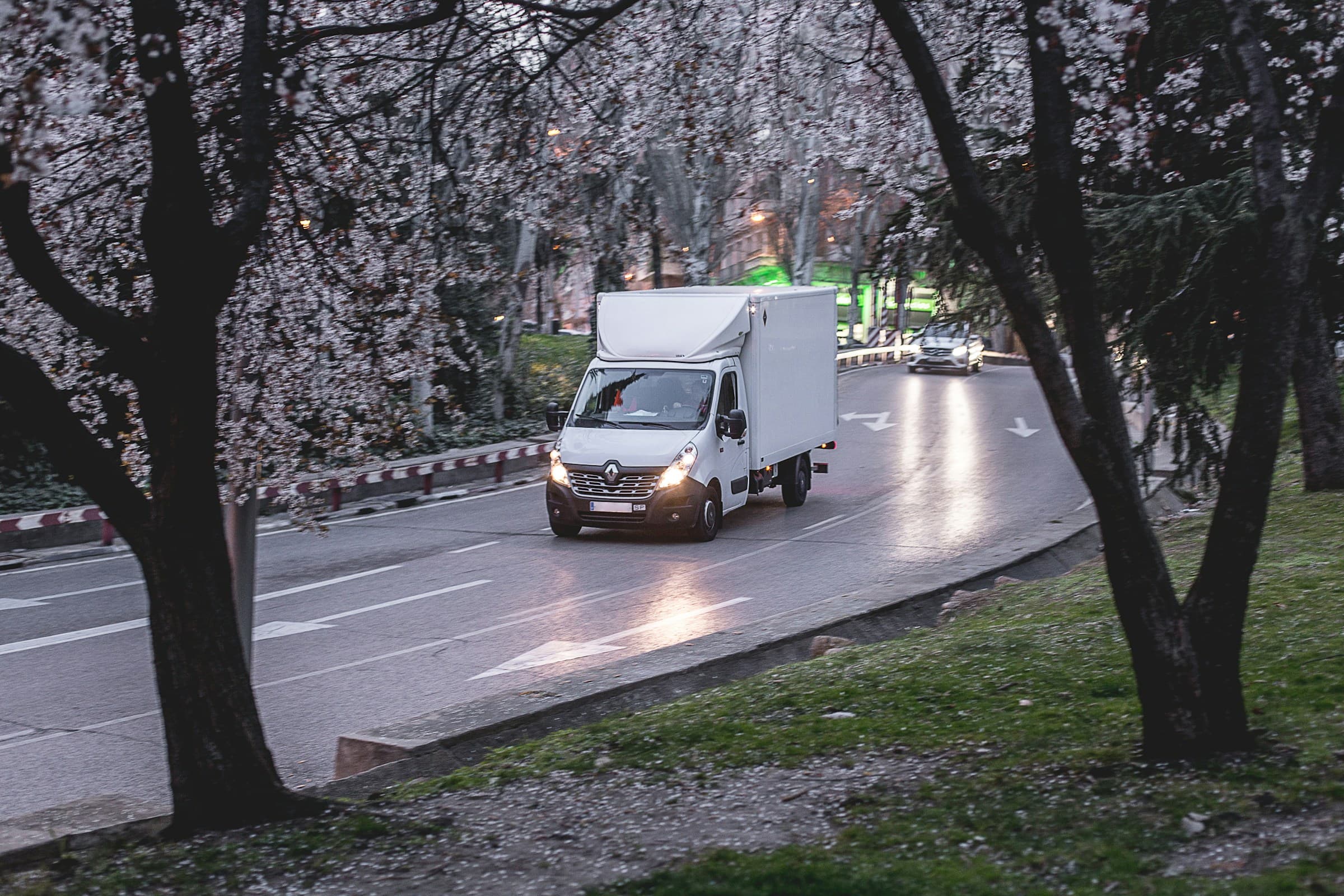 Delivery van moving along a tree-lined road